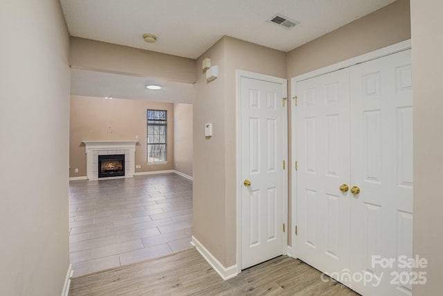 entryway featuring baseboards, visible vents, wood finished floors, and a tile fireplace