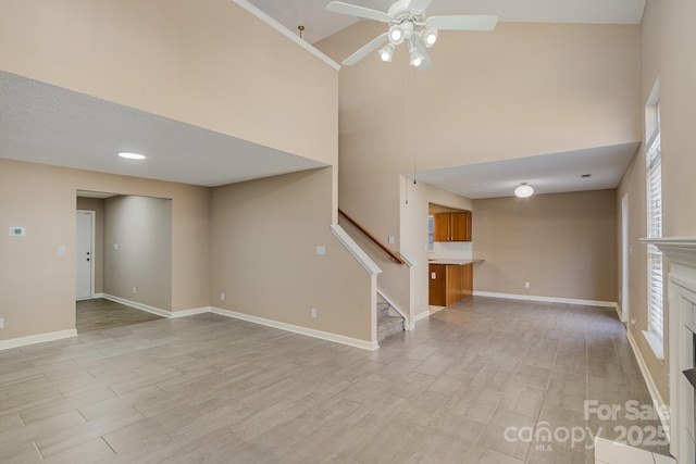 unfurnished living room with stairs, light wood-type flooring, a fireplace, and baseboards