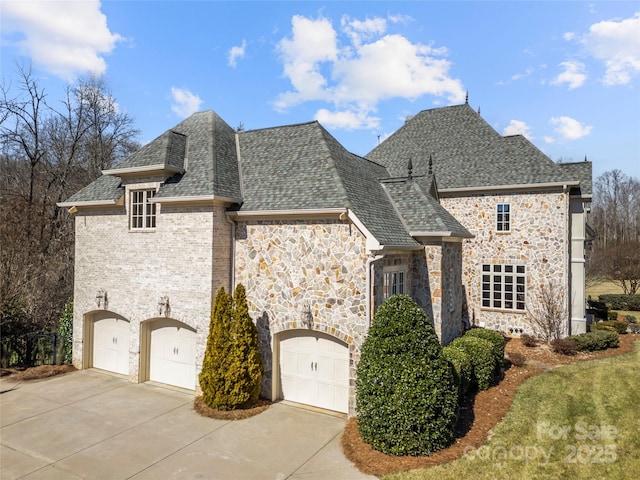 view of front of home with a shingled roof, stone siding, driveway, and a garage