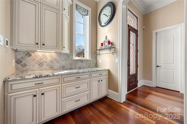 interior space with dark wood-style floors, ornamental molding, light stone counters, and tasteful backsplash