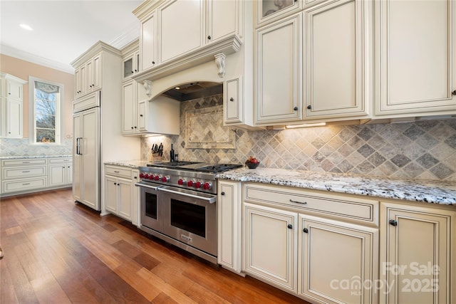 kitchen with ornamental molding, cream cabinets, high end appliances, and glass insert cabinets