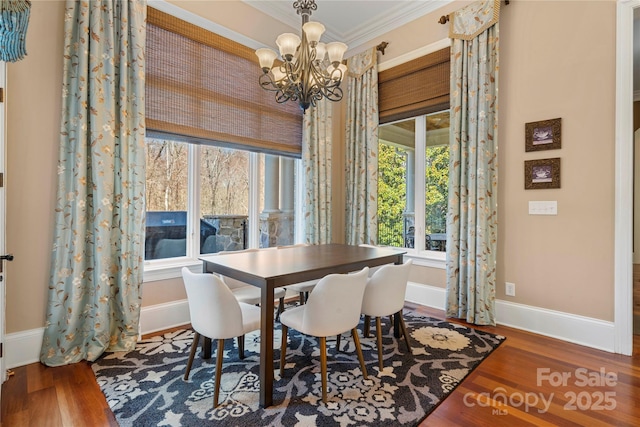 dining space with baseboards, ornamental molding, a notable chandelier, and wood finished floors