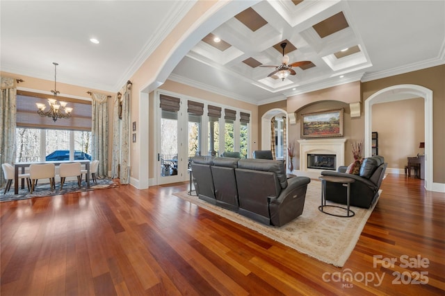 living room featuring crown molding, dark wood-type flooring, a glass covered fireplace, and a healthy amount of sunlight