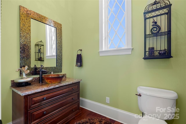 half bath featuring toilet, baseboards, wood finished floors, and vanity