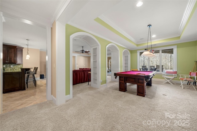 rec room featuring arched walkways, light carpet, french doors, a raised ceiling, and crown molding