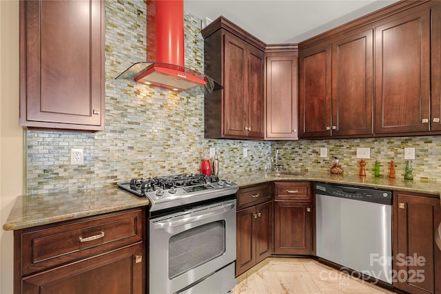 kitchen with light stone countertops, wall chimney range hood, appliances with stainless steel finishes, and a sink