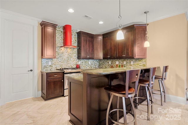 kitchen featuring pendant lighting, wall chimney exhaust hood, gas stove, a peninsula, and a kitchen breakfast bar