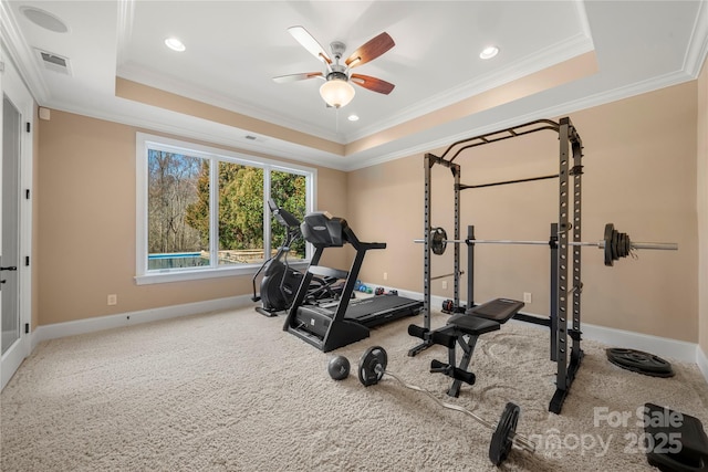 exercise area featuring carpet floors, a tray ceiling, ornamental molding, and baseboards