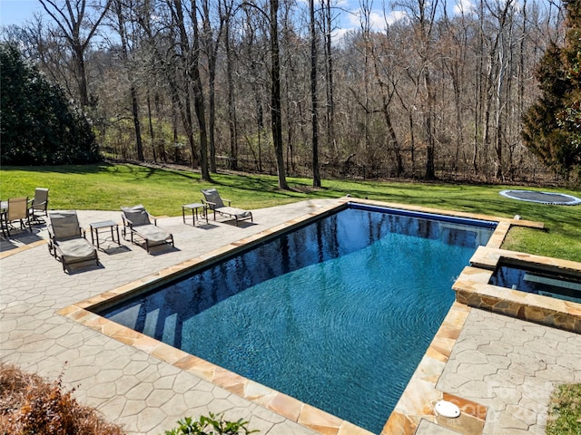 pool featuring a yard, a trampoline, a patio area, and an in ground hot tub