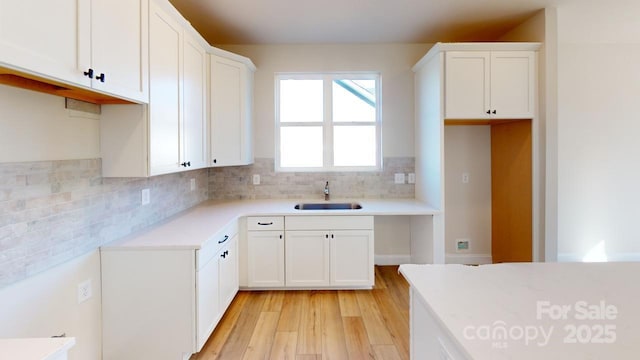 kitchen featuring white cabinets, backsplash, light hardwood / wood-style flooring, and sink