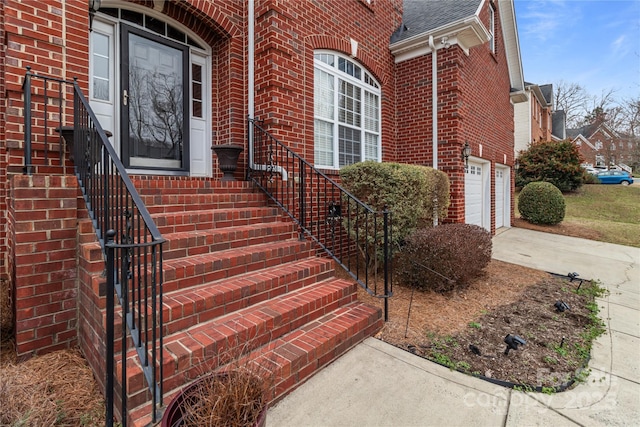 entrance to property featuring concrete driveway, brick siding, and roof with shingles