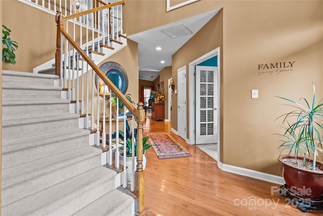 entrance foyer with visible vents, baseboards, stairway, wood finished floors, and recessed lighting