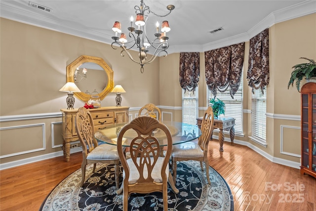 dining space with crown molding, hardwood / wood-style floors, visible vents, and a notable chandelier