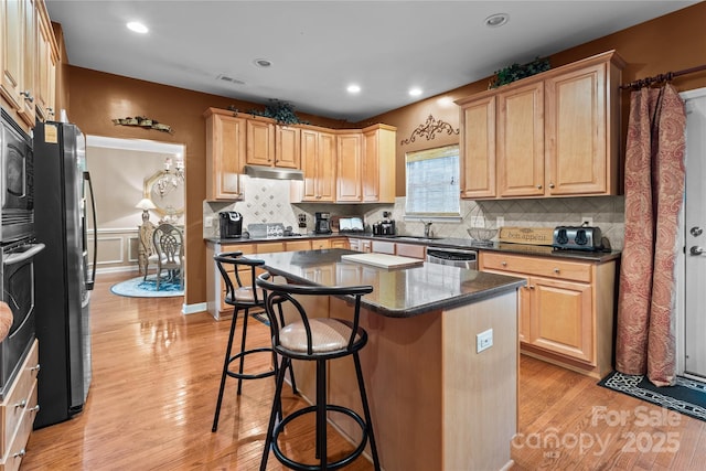 kitchen with a center island, a breakfast bar area, stainless steel appliances, visible vents, and light wood-style flooring