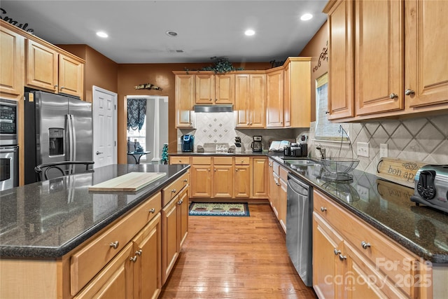 kitchen with recessed lighting, a kitchen island, light wood-style floors, appliances with stainless steel finishes, and tasteful backsplash