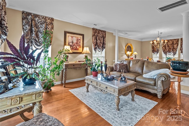 living area with a notable chandelier, visible vents, ornamental molding, ornate columns, and hardwood / wood-style flooring