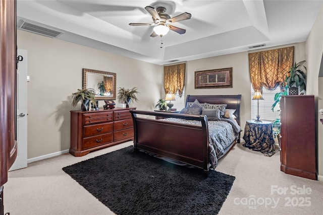 bedroom with a tray ceiling, carpet, and visible vents