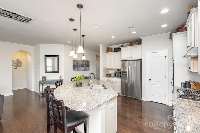 kitchen featuring arched walkways, stainless steel appliances, a sink, visible vents, and dark wood-style floors