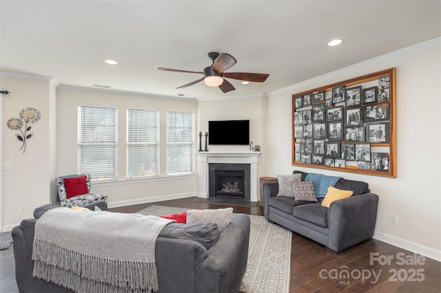 living area with a fireplace with flush hearth, baseboards, dark wood finished floors, and crown molding