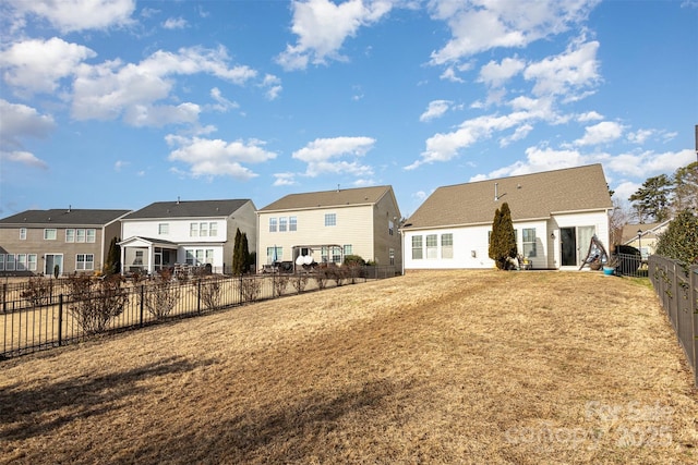 rear view of property with a fenced backyard, a residential view, and a yard