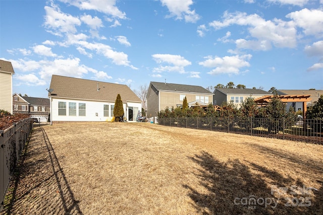 rear view of property featuring a fenced backyard and a residential view