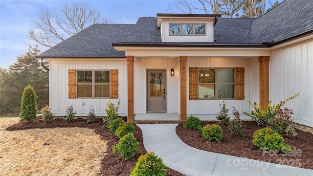 view of exterior entry featuring a porch and a shingled roof