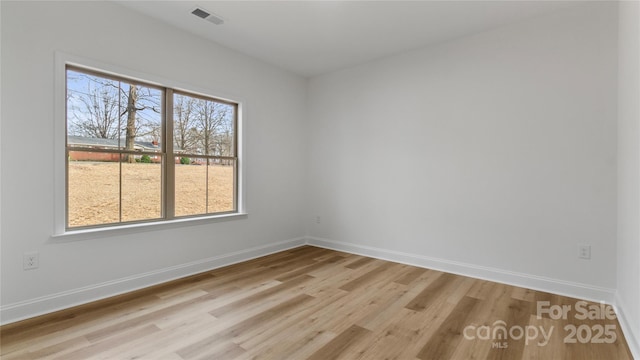 unfurnished room featuring visible vents, light wood-style floors, and baseboards