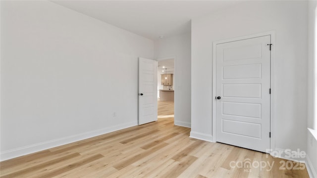 unfurnished bedroom with light wood-style flooring and baseboards