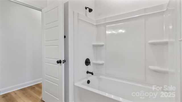 bathroom with baseboards, shower / tub combination, and wood finished floors