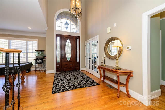 entryway with light wood-type flooring, a healthy amount of sunlight, and ornamental molding