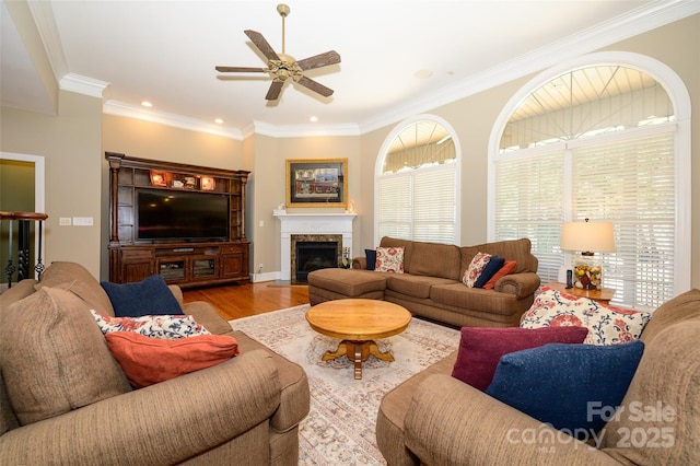 living area featuring crown molding, a fireplace, recessed lighting, ceiling fan, and wood finished floors