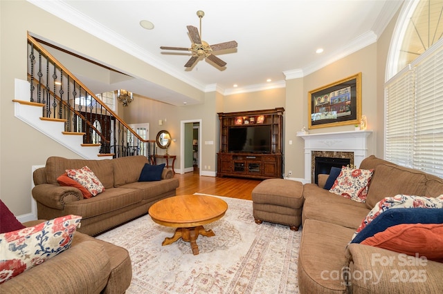 living area with light wood finished floors, stairs, crown molding, and a high end fireplace