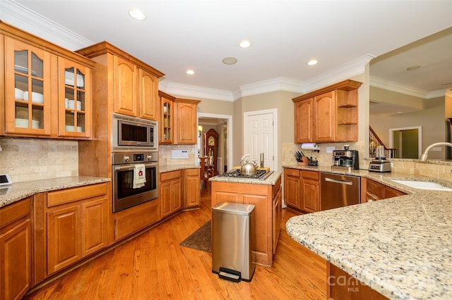 kitchen featuring glass insert cabinets, appliances with stainless steel finishes, light stone counters, open shelves, and a sink