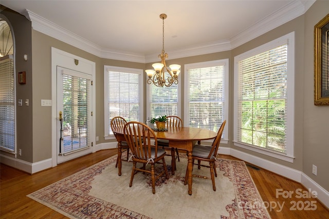 dining room with crown molding, a notable chandelier, and wood finished floors