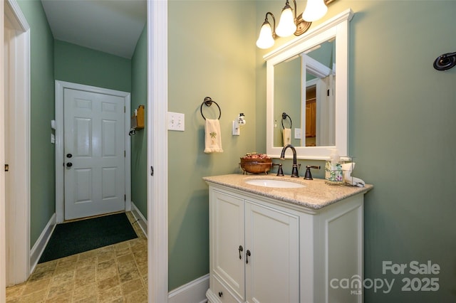 bathroom featuring baseboards, a chandelier, and vanity