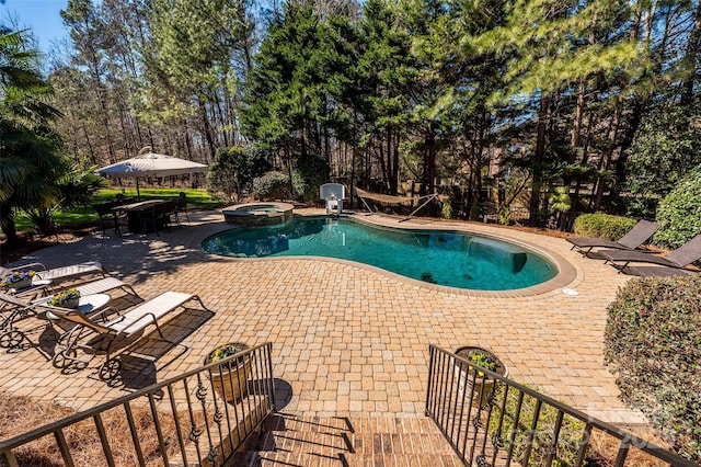 view of pool with a pool with connected hot tub, fence, and a patio