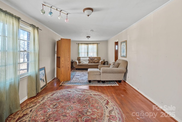 living room featuring baseboards, wood finished floors, rail lighting, and crown molding