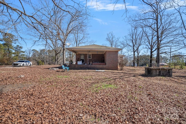 back of house with a porch and brick siding