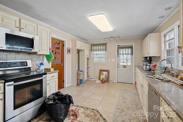 kitchen featuring decorative backsplash, ornamental molding, stainless steel appliances, a sink, and light tile patterned flooring