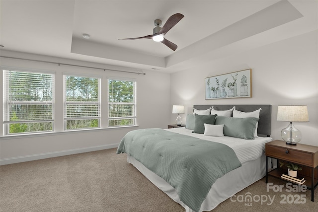 bedroom featuring a ceiling fan, a tray ceiling, carpet flooring, and baseboards