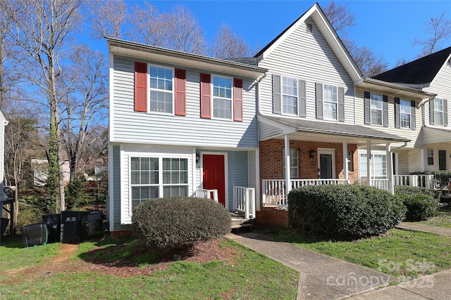 view of front of house featuring brick siding, a porch, and a front yard