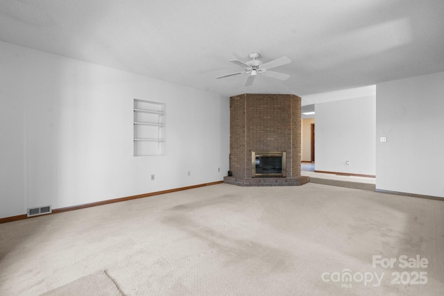 unfurnished living room with carpet flooring, a ceiling fan, visible vents, built in features, and a brick fireplace