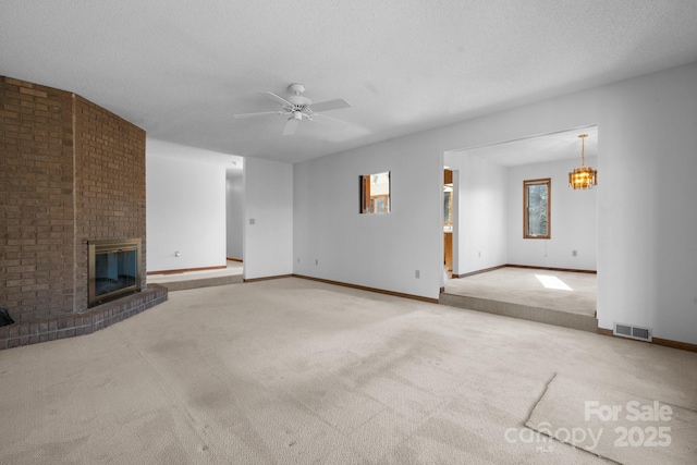 unfurnished living room with a brick fireplace, a textured ceiling, visible vents, and carpet flooring