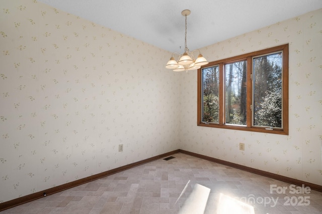 spare room with baseboards, a chandelier, and wallpapered walls