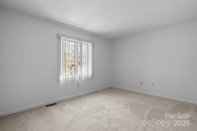 unfurnished room featuring light carpet, a textured ceiling, visible vents, and baseboards