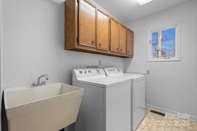 laundry room featuring a sink, visible vents, baseboards, cabinet space, and washer and clothes dryer