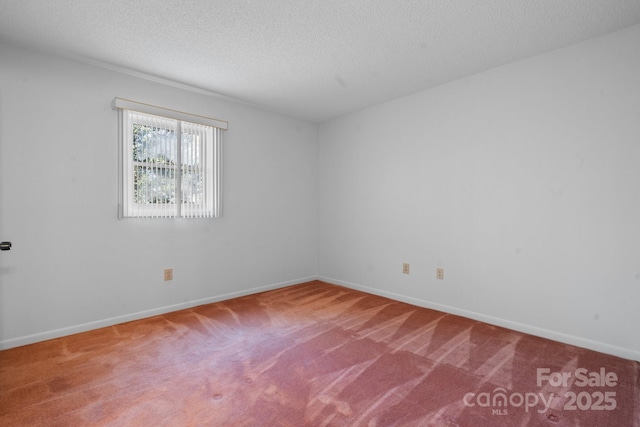 carpeted spare room featuring a textured ceiling and baseboards