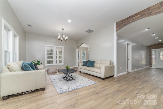 living area with a chandelier, visible vents, baseboards, and wood finished floors