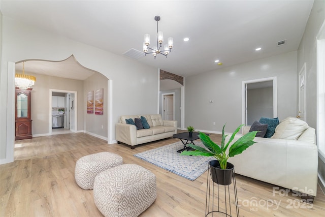 living room featuring arched walkways, recessed lighting, visible vents, an inviting chandelier, and wood finished floors