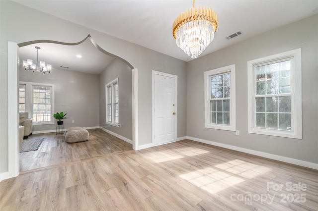 entrance foyer featuring baseboards, visible vents, a chandelier, and wood finished floors